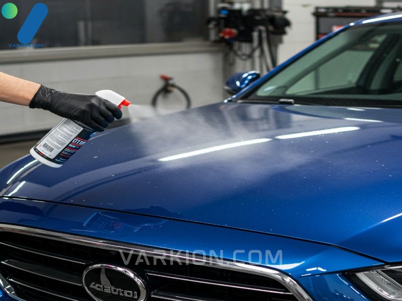 a-detailer-applies-a-spray-wax-to-a-metallic-blue-cars-hood-showing-an-immediate-water-beading-effect