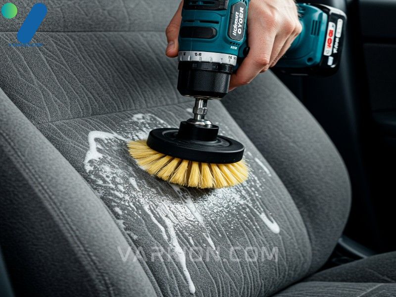 close-up-of-a-drill-brush-scrubbing-a-heavily-stained-gray-fabric-car-seat-lifting-foam-and-dirt