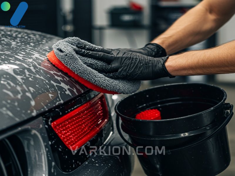 close-up-of-a-hand-in-a-wash-bucket-showing-a-red-grit-guard-and-a-microfiber-wash-mitt