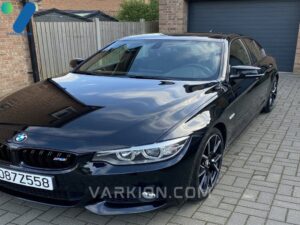 coche-negro-brillante-detallado-en-la-entrada-reflejando-el-cielo-azul