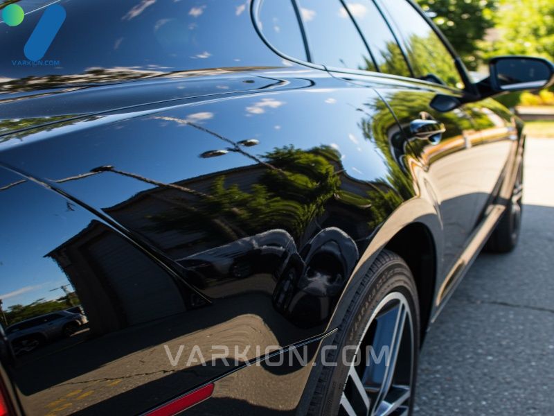highly-polished-black-car-fender-reflecting-the-sky-and-trees-like-a-mirror