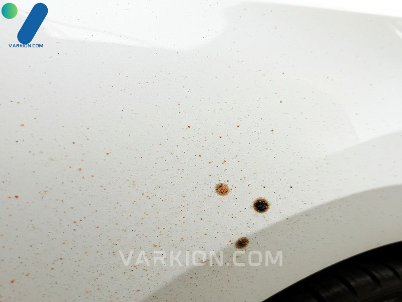 macro-shot-of-a-white-car-panel-contaminated-with-orange-rail-dust-and-black-tar